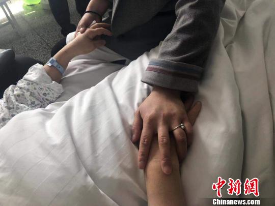 图为一名伤员的女儿抓着她的手进行安抚。　李庭耀 摄