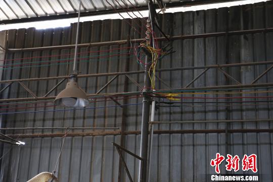 柳州市柳南区太阳村镇山头村张表屯一家木门加工作坊，电线架在铁柱上。　朱柳融 摄