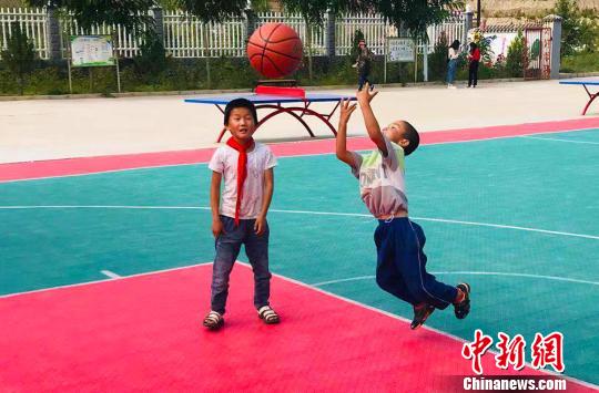 图为布楞沟村小学学生在新修的篮球场上玩篮球。　艾庆龙 摄