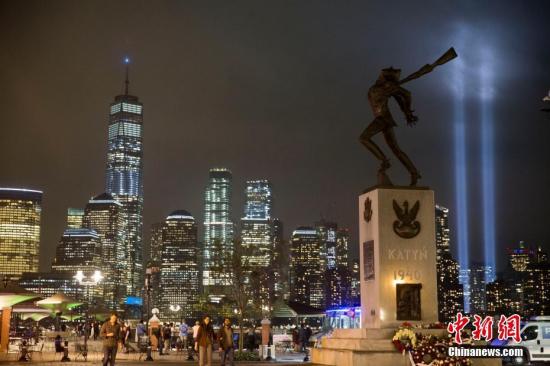 资料图：当地时间2018年9月11日，美国“911事件”17周年，纽约世贸中心附近两根象征着世贸中心双子塔的蓝色光柱直冲云霄，一直持续到黎明。图为从泽西市透过城市雕塑遥望灯柱。<a target=