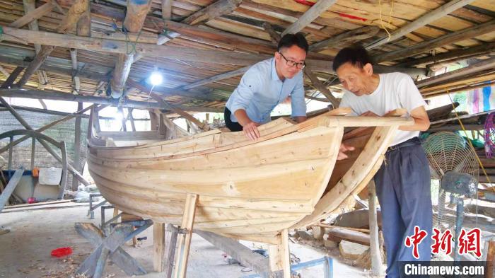 图为连家渔船复建过程中郑文祥(右)向其孙子郑煜元传授建造技巧。　吕雷 摄