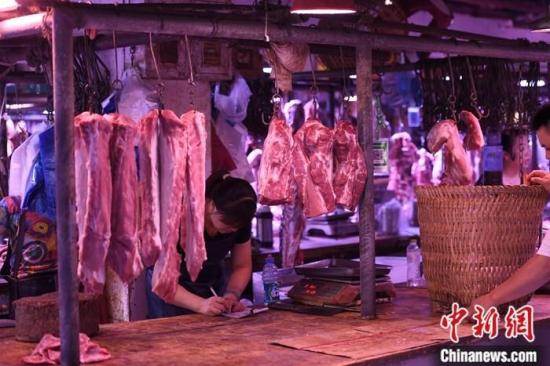 资料图为重庆一农贸市场内的商家挂满充足的猪肉。<a target=
