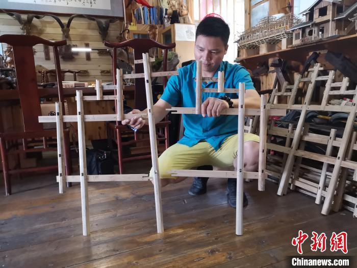 杨云东展示侗族木构建筑模型，木块之间无需钉子连接。　林馨 摄