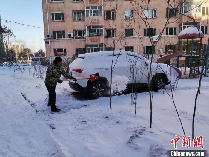 哈尔滨市一小区居民在清理车辆旁边的积雪。　姜辉 摄