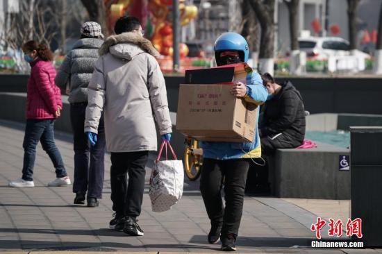 2月10日，一名外送员怀抱纸箱走出金融街购物中心。复工首日，北京金融街地区人流渐增。<a target=