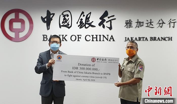图为印尼中国商会总会主席、中国银行雅加达分行行长张朝阳(左)向印尼国家灾害管理委员会(BNPB)(右)移交捐赠款项。中国银行雅加达分行 供图