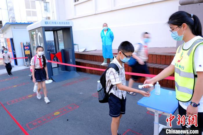 桂雅路小学桂花校区老师在校门给进入学校的学生测量体温。　蒋雪林 摄