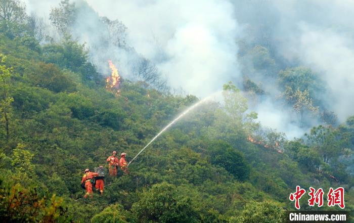 森林消防员正在通过水枪对火场扑打灭火。卢耀强摄